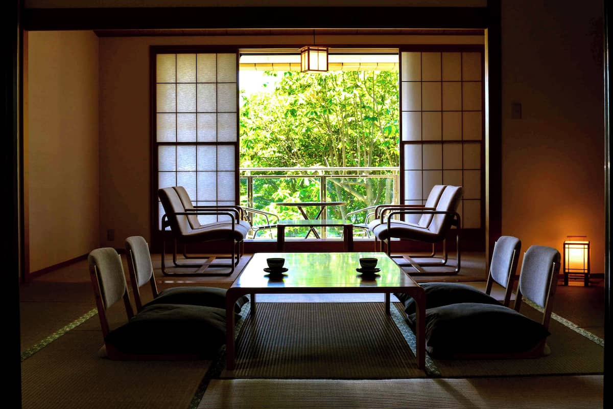 A traditional Japanese room with tatami flooring, a low table, and chairs.