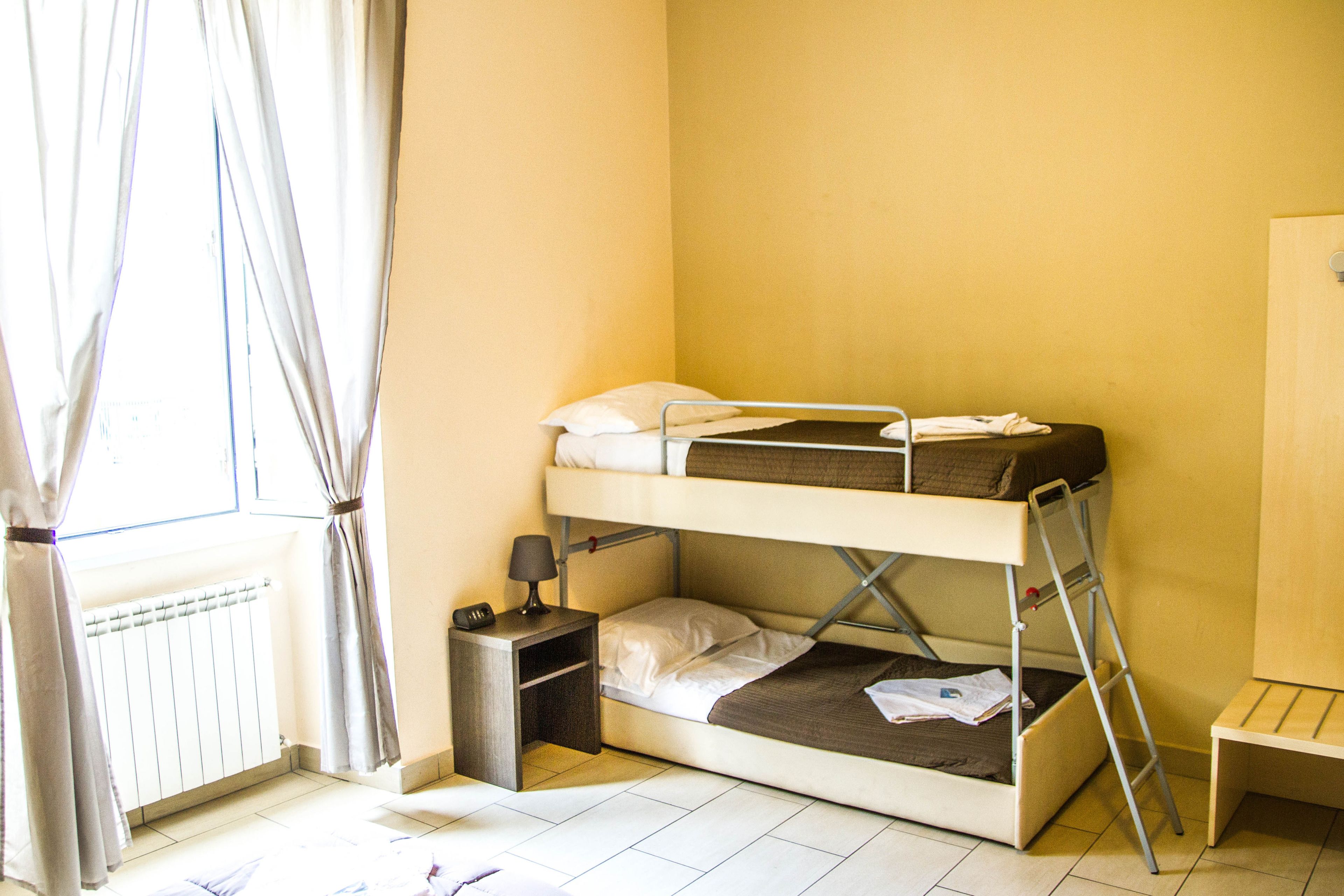 A bunk bed with a ladder, a small bedside table with a lamp, and a radiator.