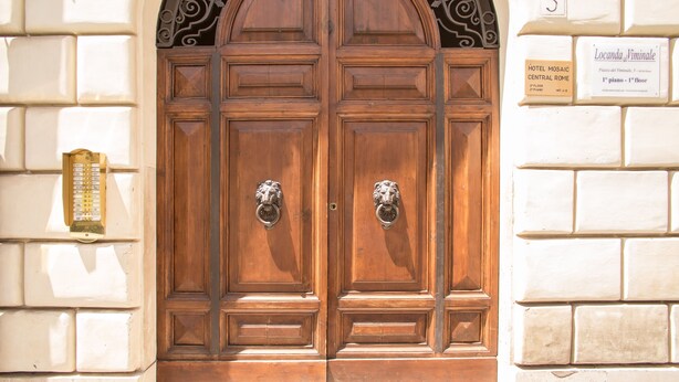 A double wooden door with ornate metal handles, a number '5' sign, and a hotel sign indicating 'Locanda del Viminale' on the 1st floor. - Mosaic Guest House (Rome)