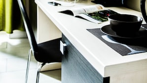 A modern hotel room with a desk, a vase of flowers, a laptop, and a chair. - Mosaic Guest House (Rome)