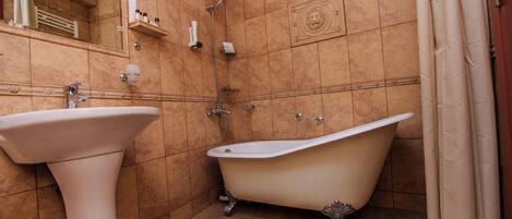 A bathroom with a freestanding bathtub, a pedestal sink, and a mirror.