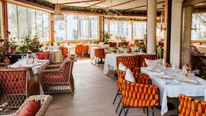 An indoor dining area with tables set for meals, wicker chairs, and large windows allowing natural light. - Aqua View Spa Boutique Hotel (Varna)