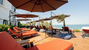 A rooftop lounge area with multiple sun loungers and umbrellas, overlooking a body of water. - Aqua View Spa Boutique Hotel (Varna)
