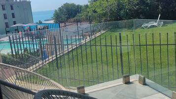 A balcony with a view of a swimming pool and the sea.