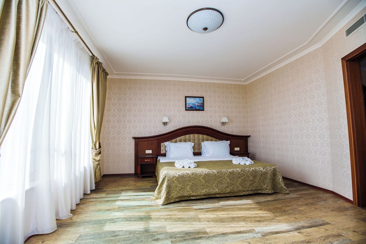 A hotel room with a large bed, a nightstand, a wall-mounted lamp, and a ceiling light.