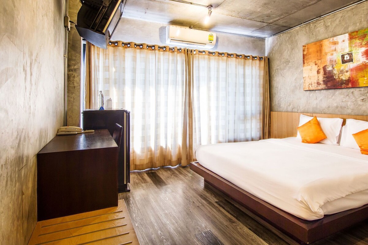 Una habitación de hotel con una cama, un escritorio, un aire acondicionado y un cuadro en la pared.