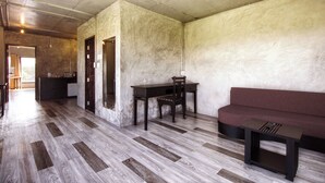 Une pièce avec un plancher en bois, une table à manger avec des chaises, un canapé et une petite table avec une lampe.
