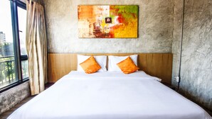 Une chambre d’hôtel avec un grand lit, une tête de lit en bois et un tableau abstrait aux couleurs vives accroché au mur.