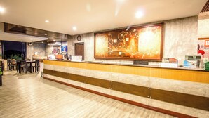 Un hall d’accueil d’hôtel avec un comptoir en bois, une grande œuvre d’art encadrée au mur et une horloge au-dessus du comptoir.