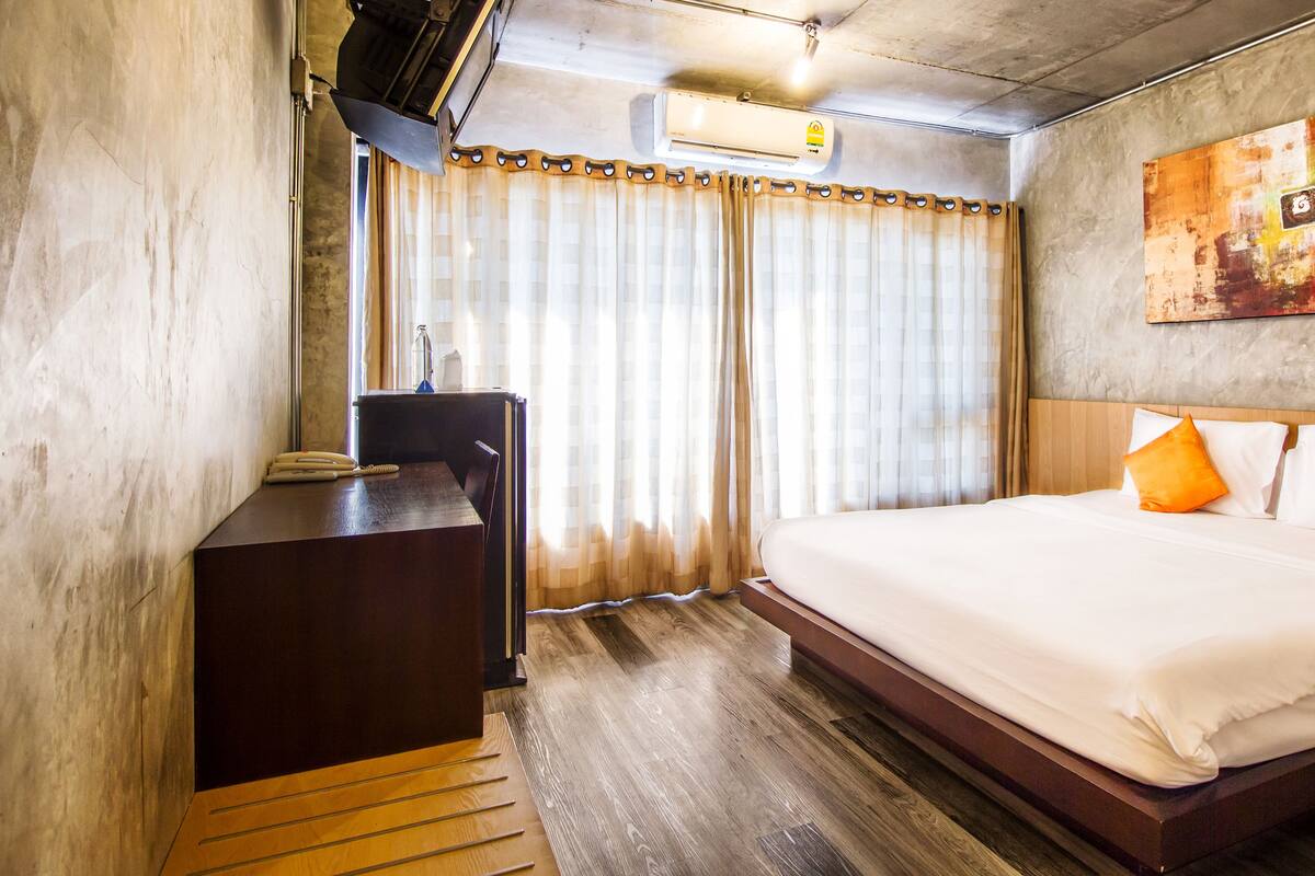 Habitación de hotel con cama, escritorio y ventana con cortinas.