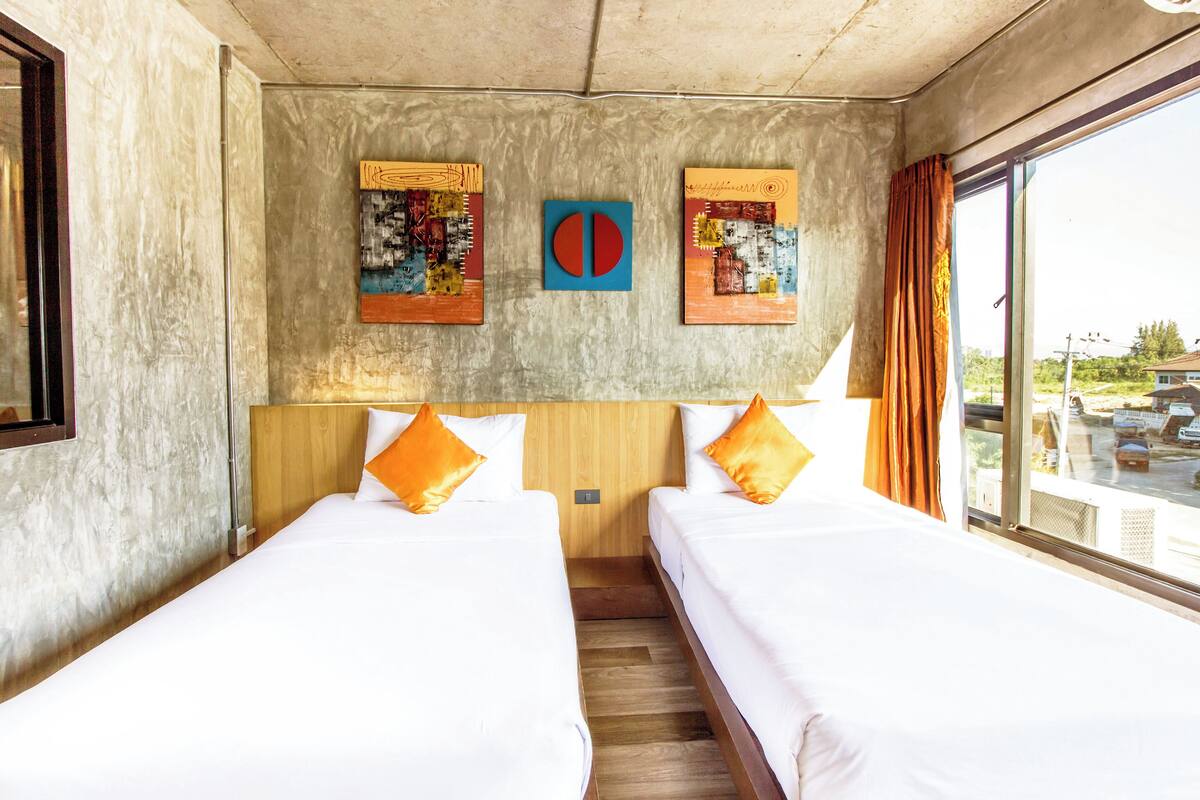 Una habitación de hotel con dos camas, una ventana con cortinas y una obra de arte en la pared.
