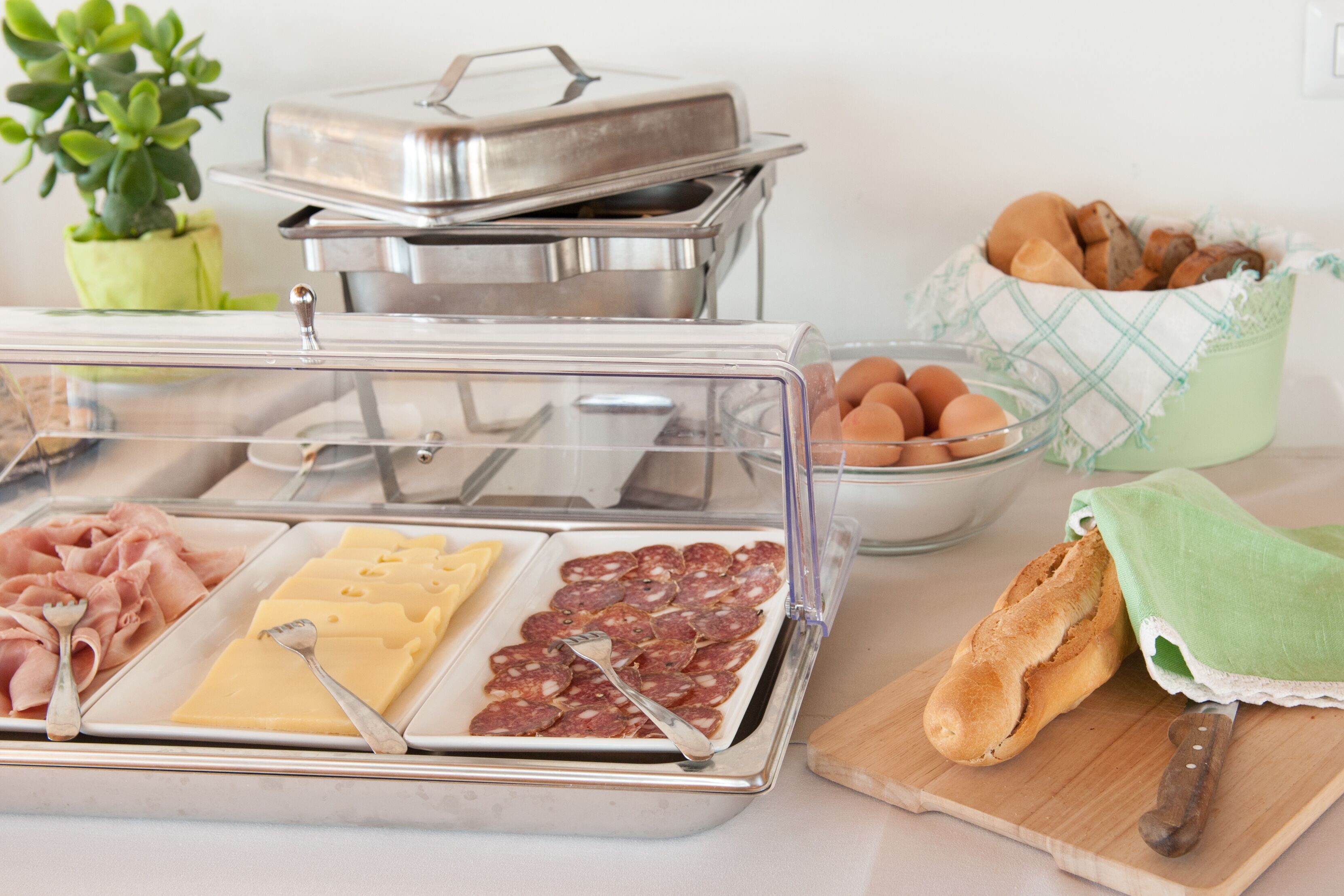 A buffet with various food items including meats, cheese, and bread.