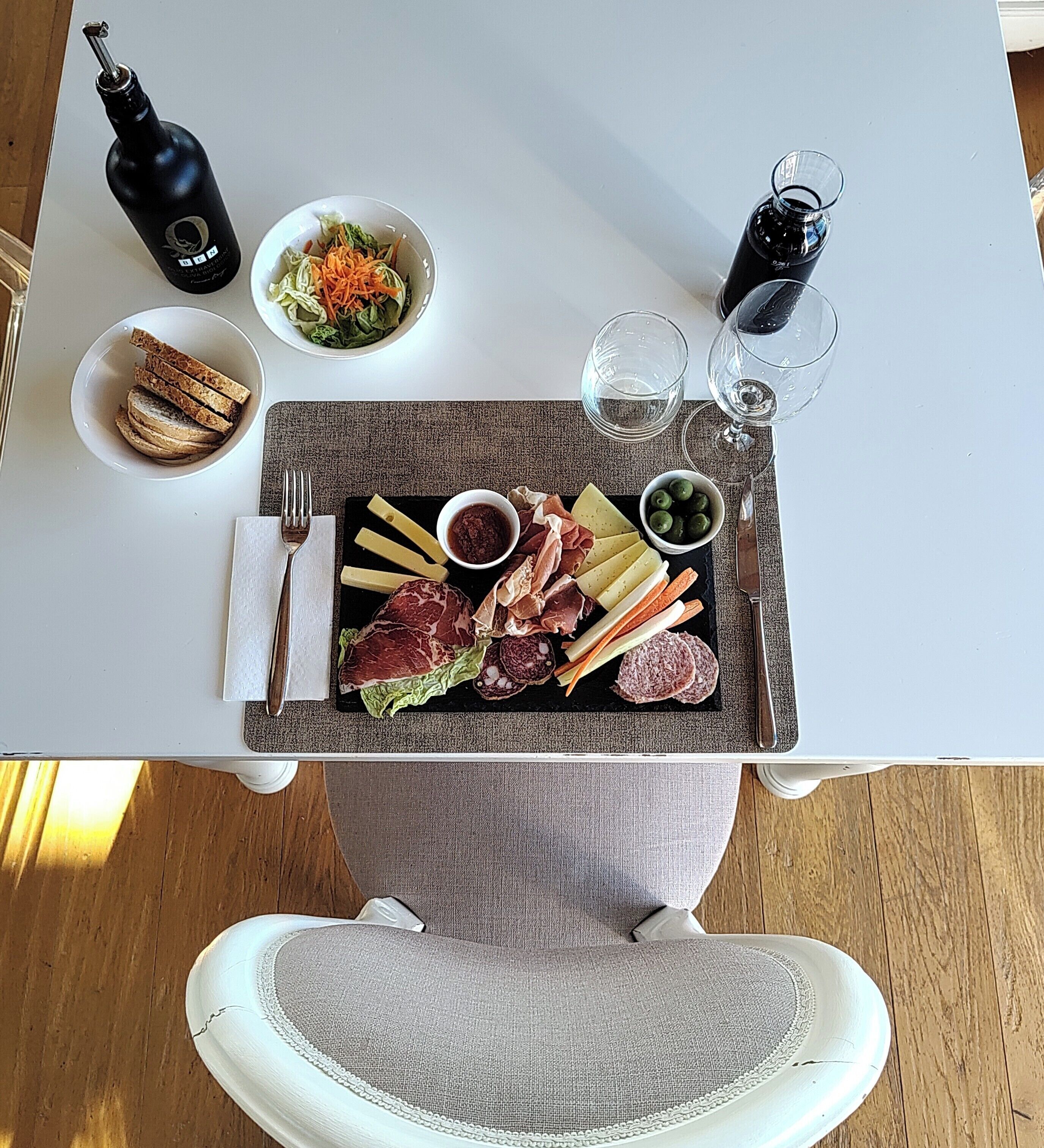 A dining table with a charcuterie board, wine glasses, and a bottle of wine.