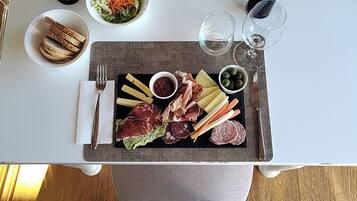 A dining table with a charcuterie board, wine glasses, and a bottle of wine.