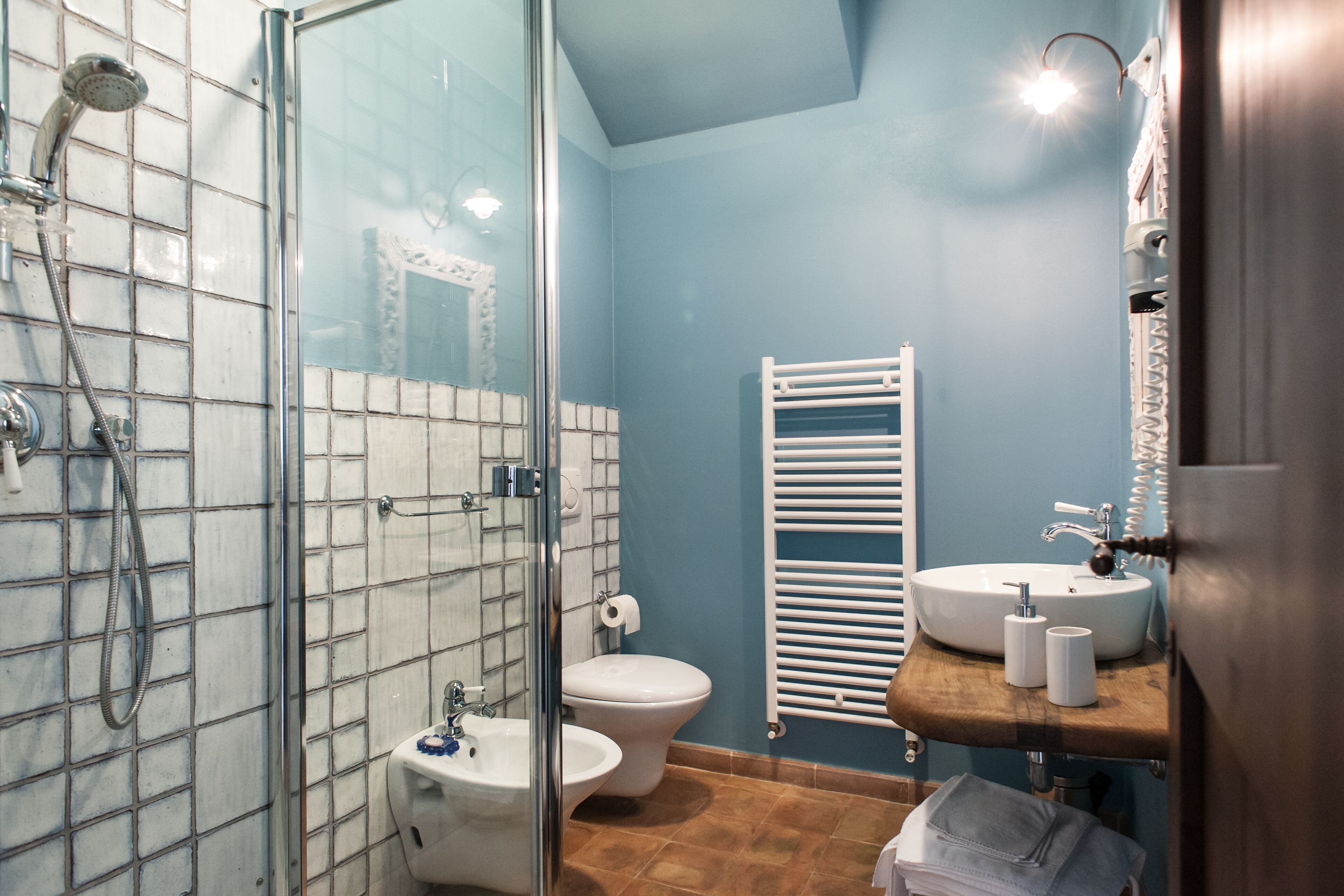 Une salle de bain avec une douche à parois de verre, des toilettes blanches, un lavabo blanc et un meuble-lavabo en bois.