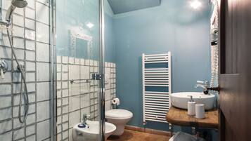 Une salle de bain avec une douche à parois de verre, des toilettes blanches, un lavabo blanc et un meuble-lavabo en bois.