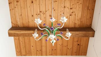 Een kroonluchter met bloemmotieven aan een houten plafond.
