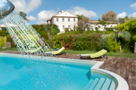 Una piscina al aire libre de temporada, sombrillas