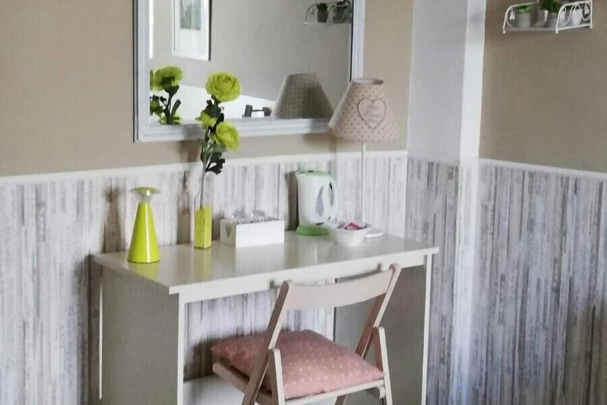 Een compacte, privé badkamer met een wastafel, een stoel, een spiegel en een plank met decoratieve objecten.