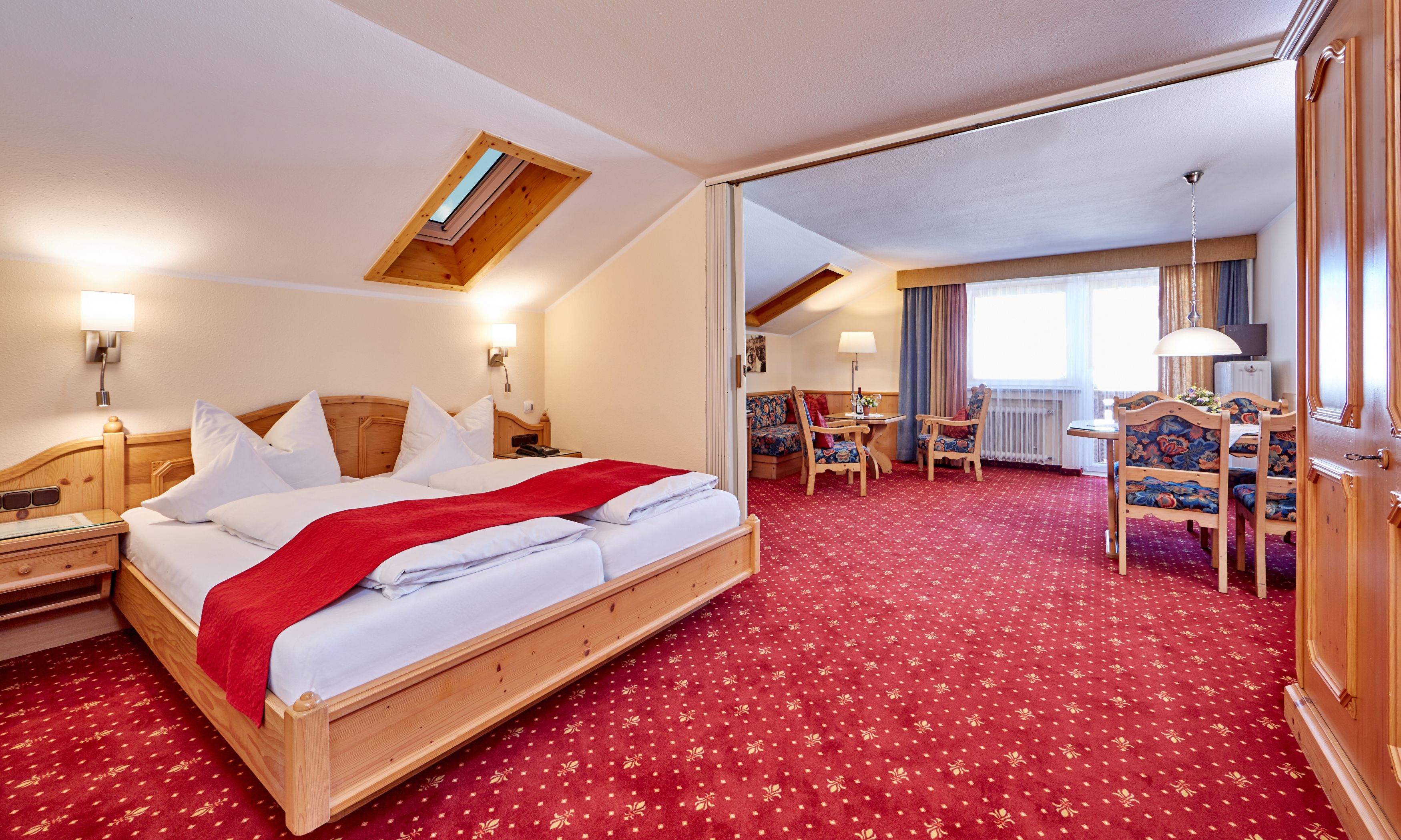 Habitación de hotel con una cama grande, un escritorio y una silla. Tiene una ventana con cortinas y vistas al exterior.