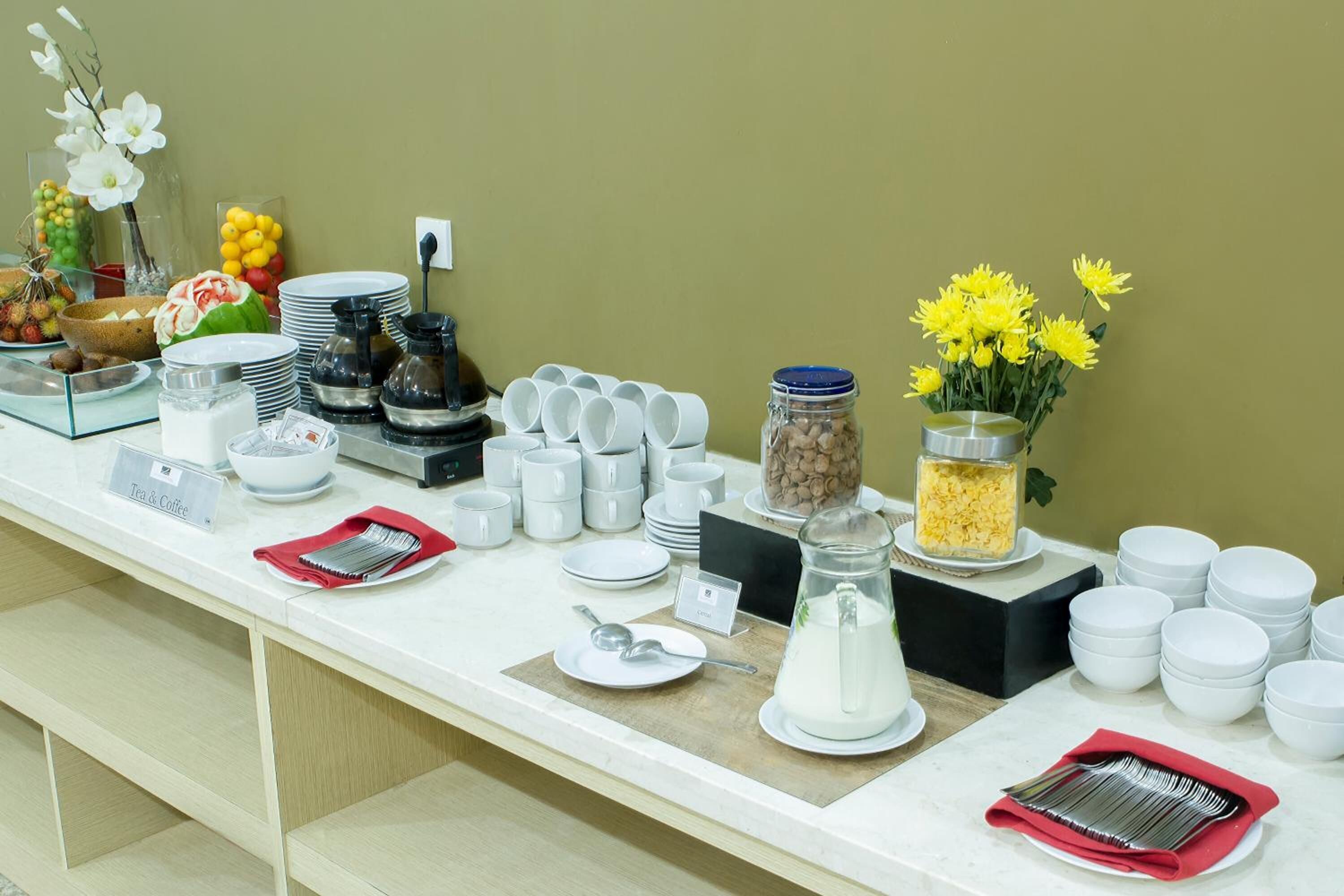 A buffet setup with various food items, utensils, and a tea & coffee station.