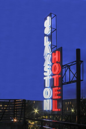 Une enseigne verticale sur laquelle figurent les mots « HÔTEL » en rouge et « HÔTEL » en blanc, sur un fond de ciel bleu foncé.