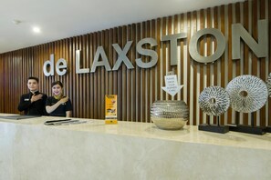 Un comptoir d’accueil avec une enseigne indiquant « de LAXSTON » et un panneau invitant à déposer des cartes de visite.