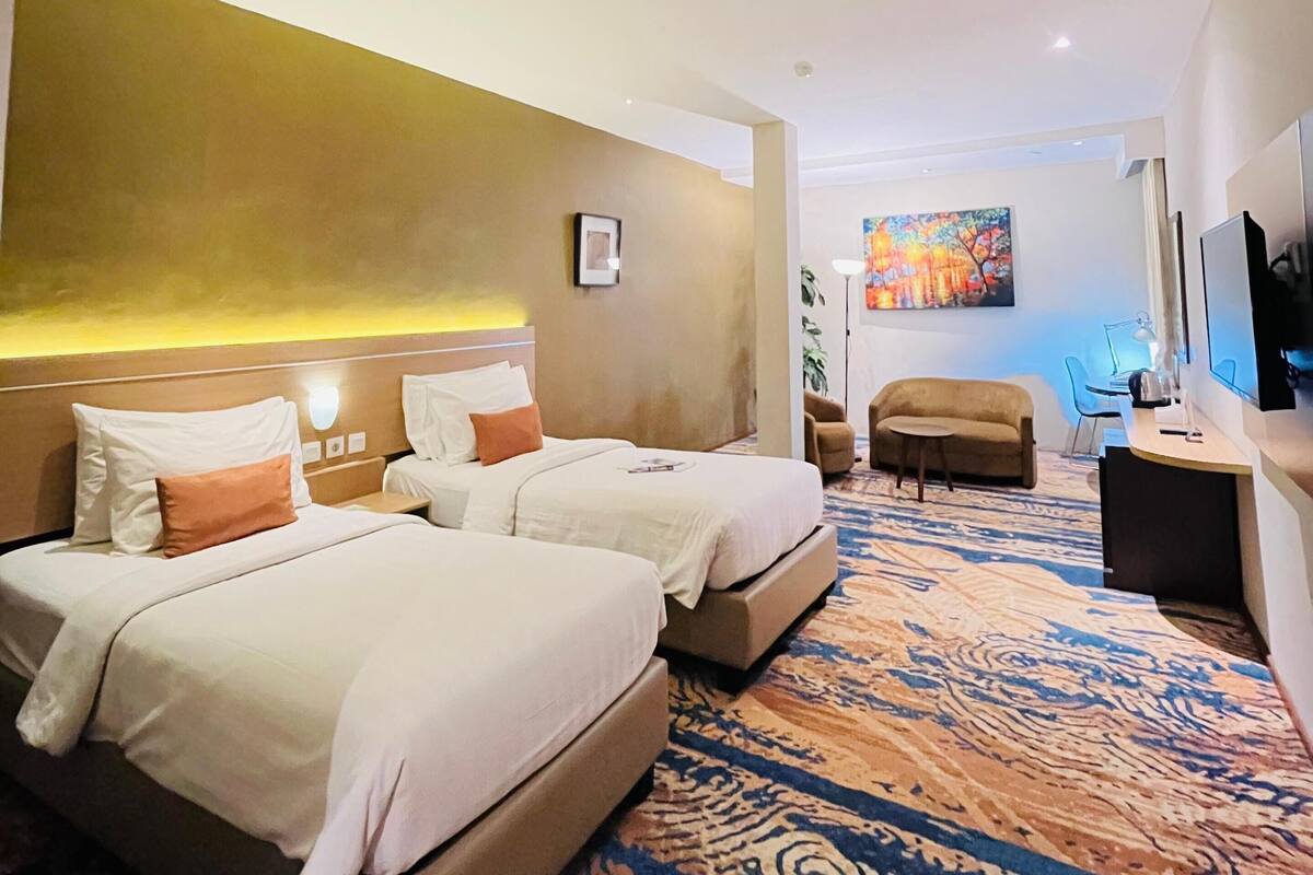 Une chambre d’hôtel avec deux lits, un canapé, un bureau et une télévision.