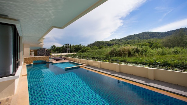 A swimming pool with a tiled deck, a view of a forested hillside, and a clear sky. - The Lago Apartments by Tropiclook (Rawai)