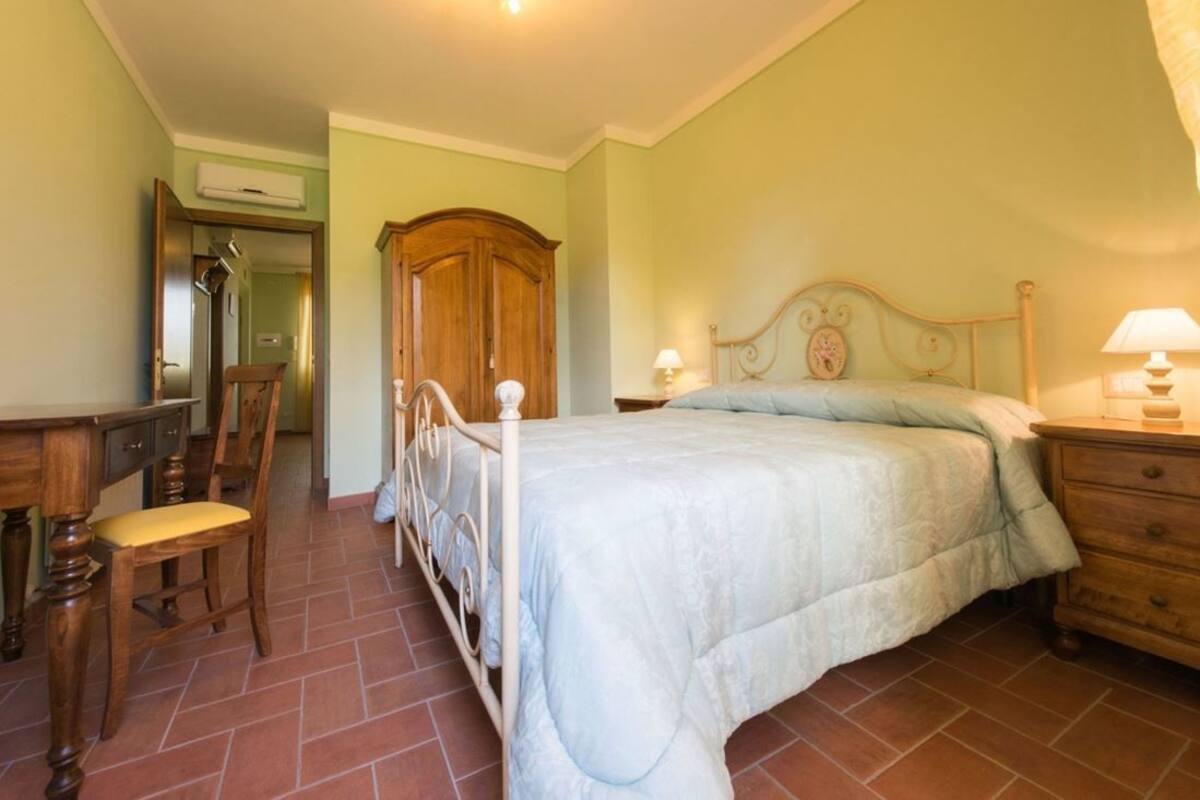 A bedroom with a bed, a chair, a dresser, and a wardrobe.