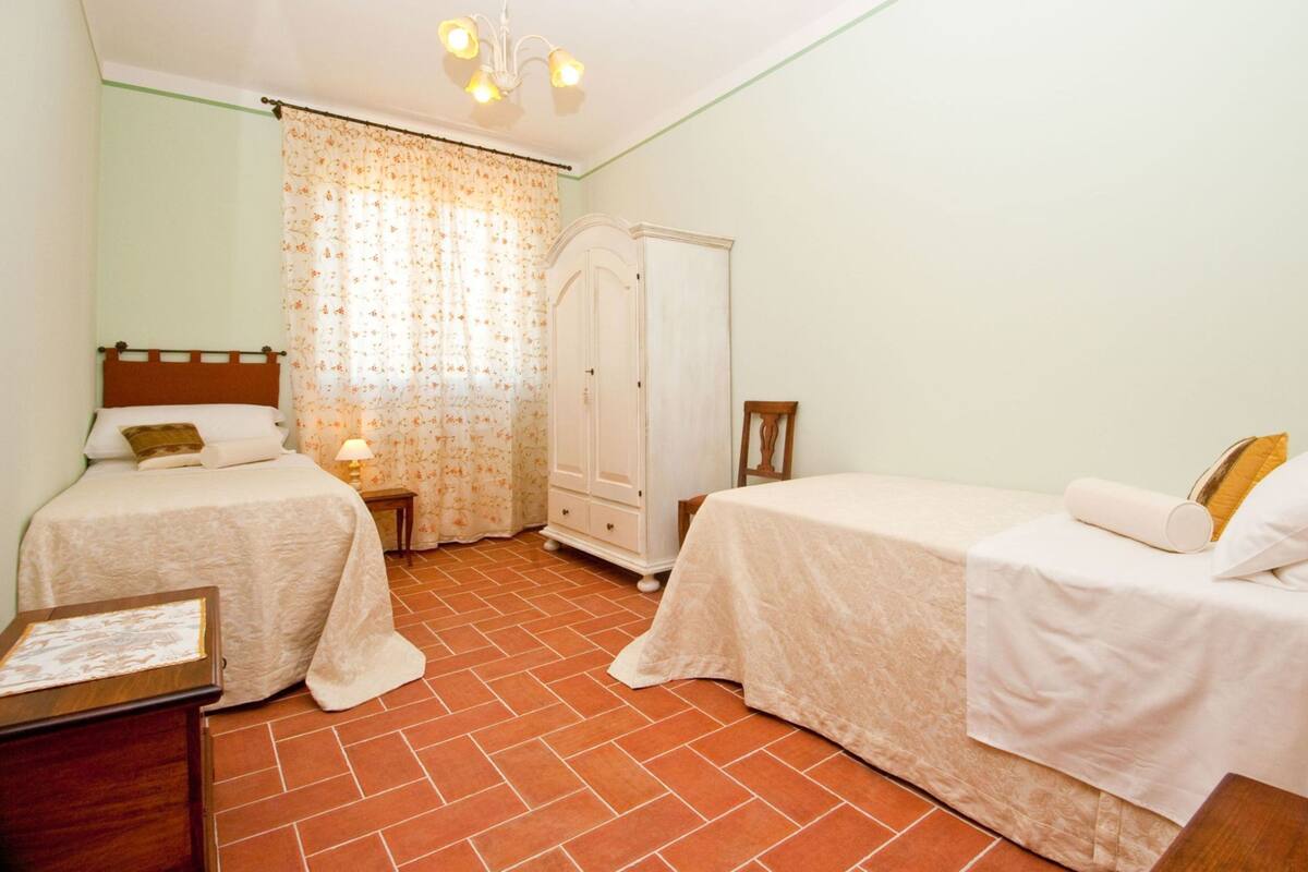 A bedroom with two single beds, a wardrobe, a small table, and a chair.