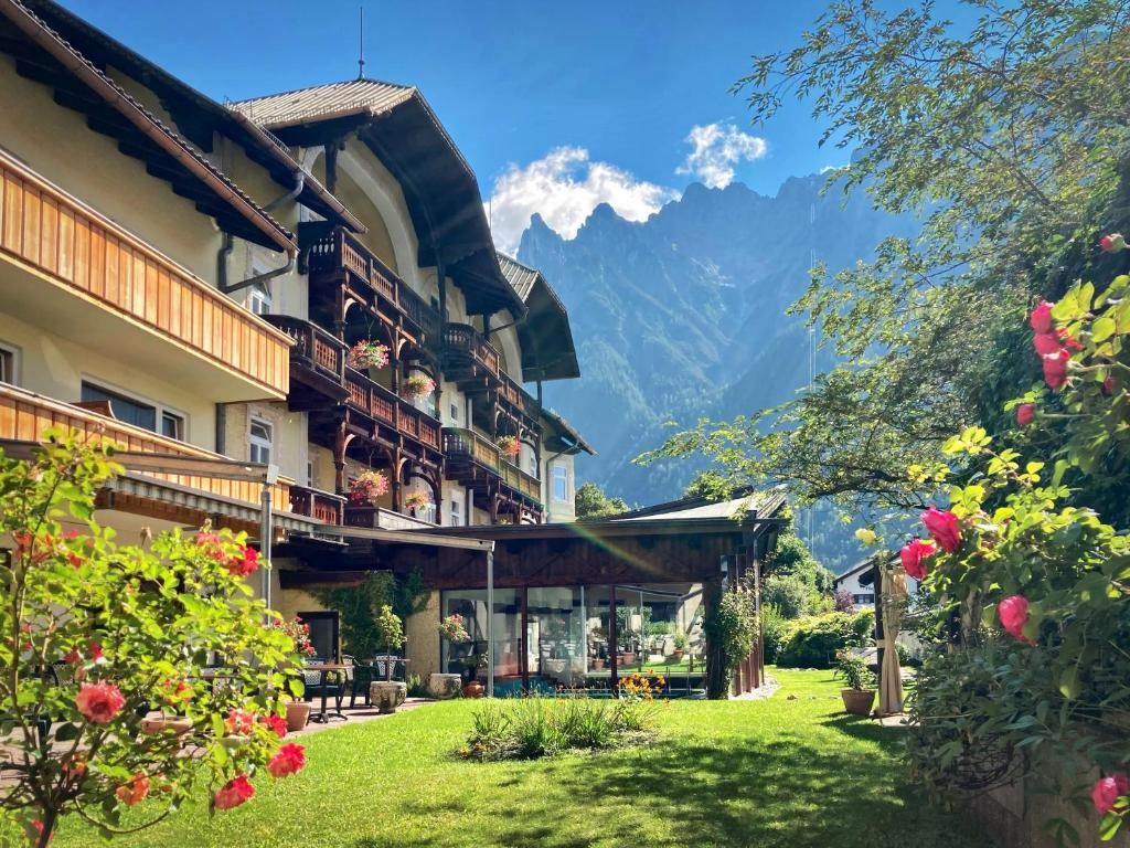 Ein traditionelles Chalet mit Balkon, einem blühenden Garten und einer Bergkulisse.