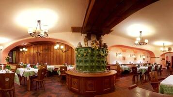 A restaurant with wooden interiors, multiple tables, and hanging chandeliers.