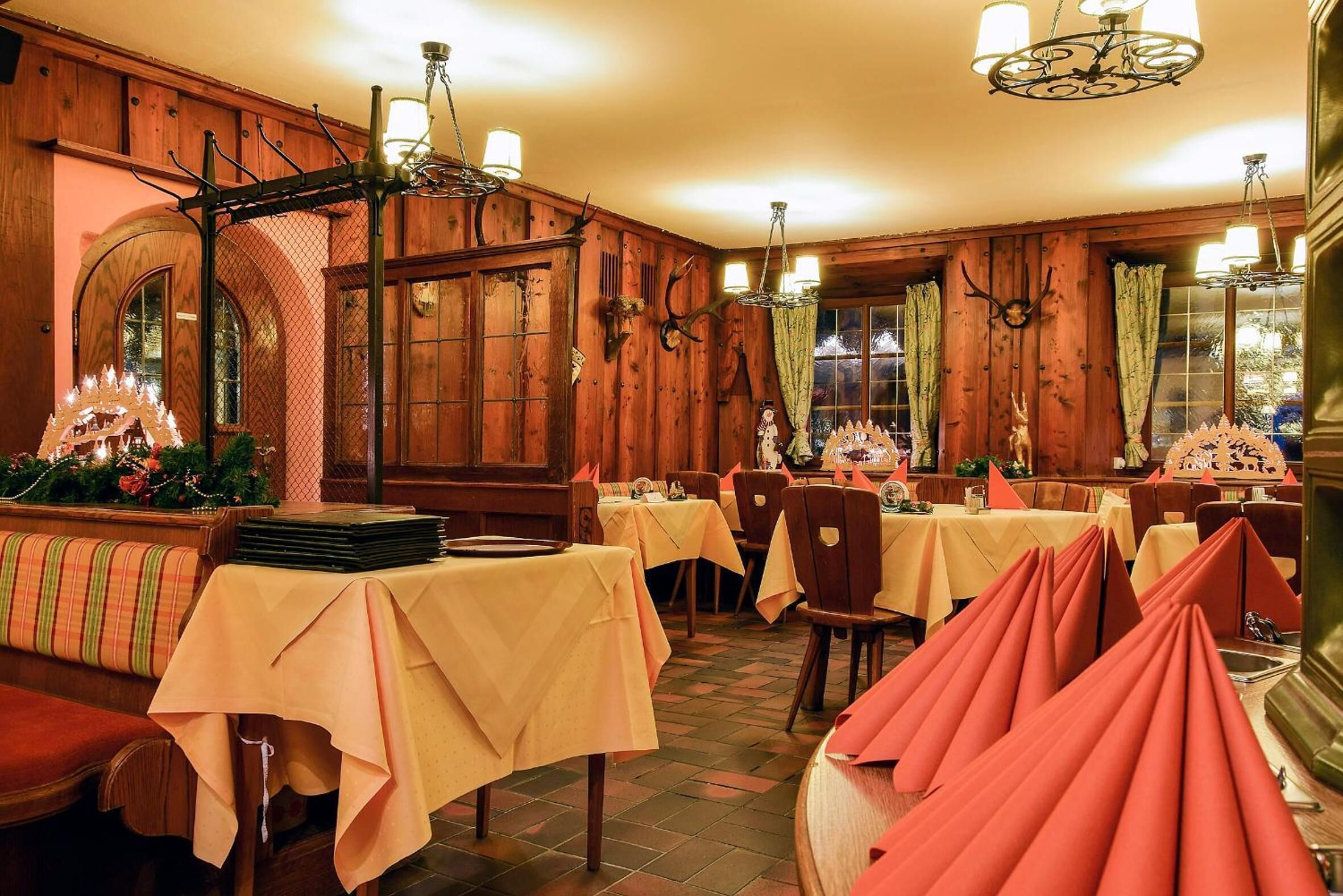 Un restaurante con paredes de madera, varias mesas con manteles amarillos y una araña.
