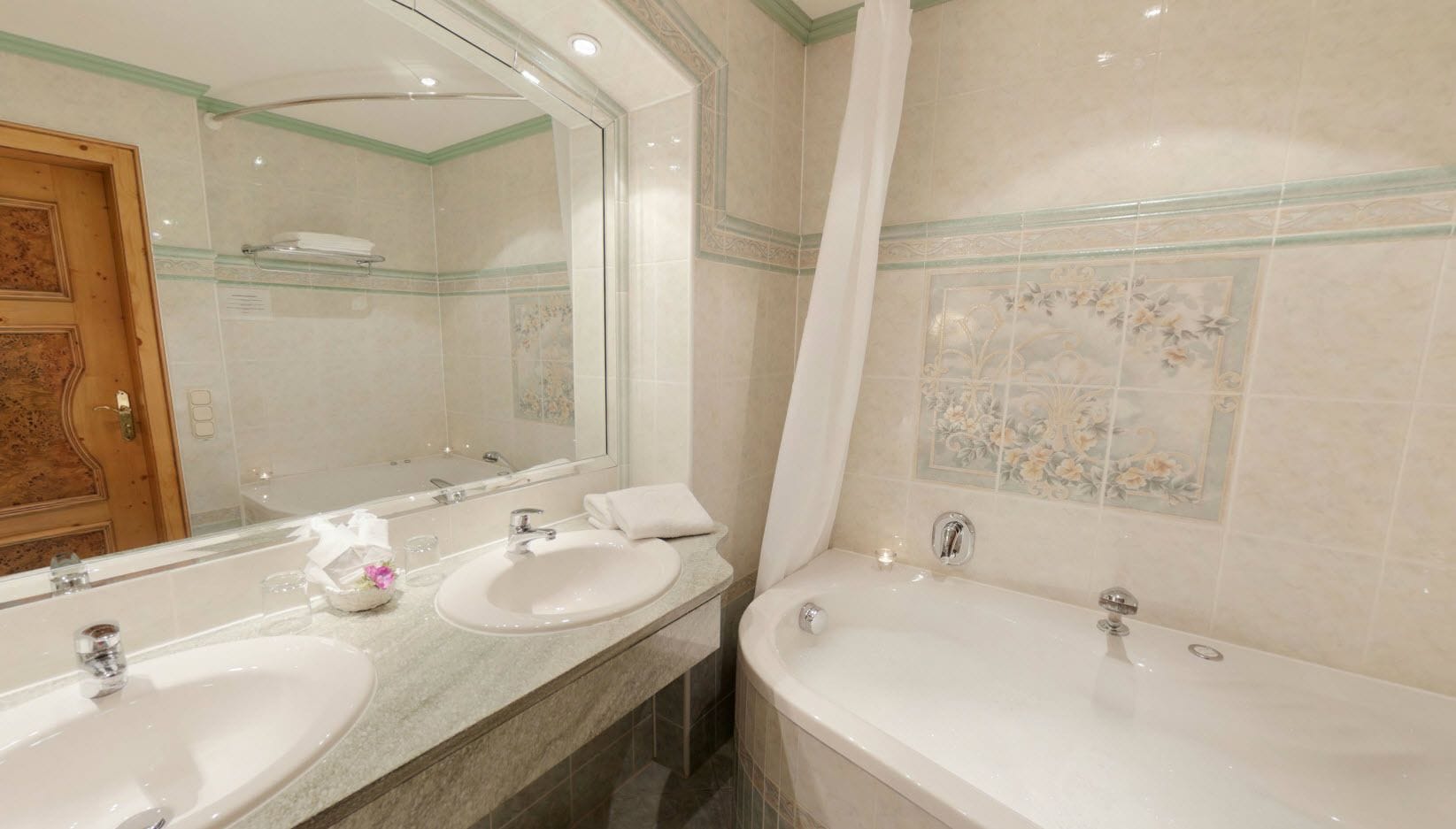 A bathroom with two sinks, a bathtub, and a large mirror.
