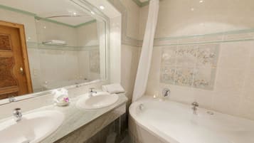 Ein Badezimmer mit zwei Waschbecken, einer Badewanne und einem großen Spiegel.