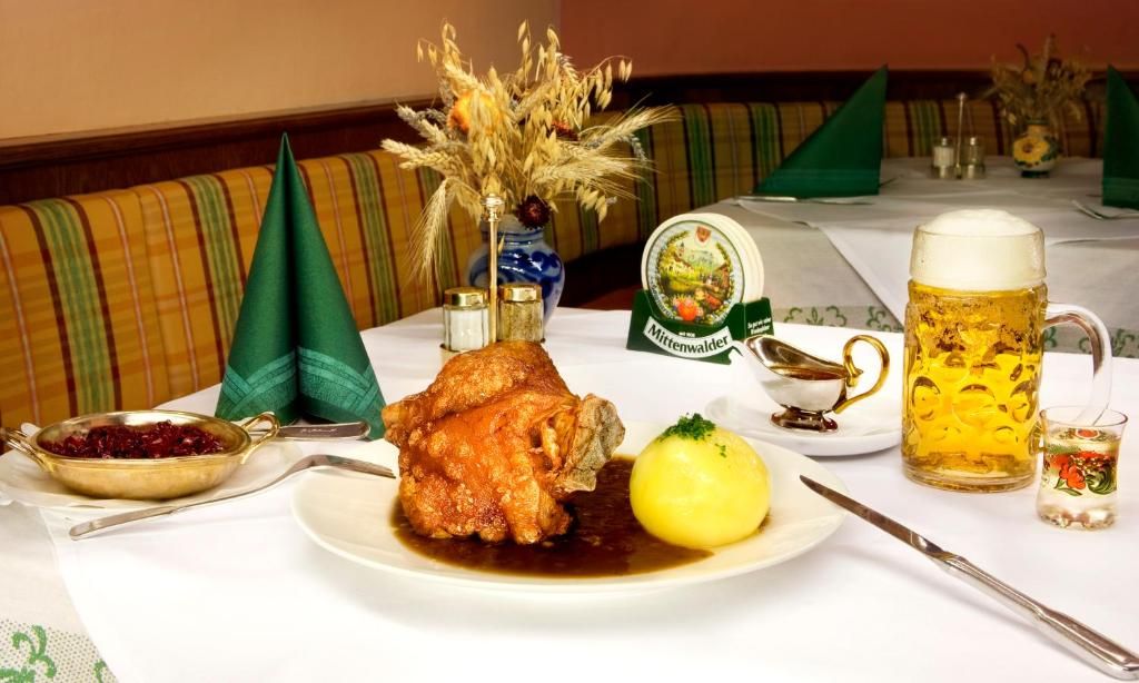 A dining table with a roasted chicken, a boiled potato, a beer mug, and a small glass of water.