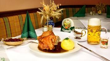 A dining table with a roasted chicken, a boiled potato, a beer mug, and a small glass of water.