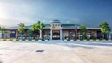 A hotel with a modern design, featuring a prominent 'NP Hotel' sign, a covered outdoor seating area, and a spacious parking lot.