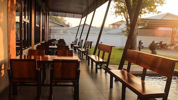 An outdoor seating area with wooden benches and tables, overlooking a street with parked motorcycles.