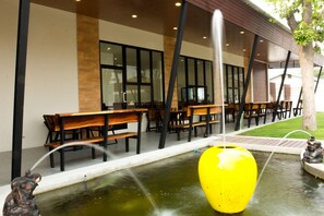 Un espace extérieur moderne, aménagé avec des bancs et un grand bac à fleurs jaune placé au centre.