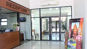 A reception area with a reception desk, a TV, and a poster of a temple. - NP Hotel (Buriram)