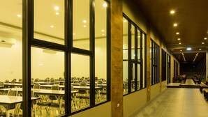 A long corridor with tables and chairs, large windows, and a ceiling with recessed lighting. - NP Hotel (Buriram)