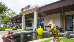 A hotel with a modern facade, outdoor seating, and a decorative fountain. - NP Hotel (Buriram)