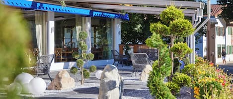 Un hôtel doté d’une terrasse extérieure, d’un patio couvert et d’un jardin agrémenté de rochers et de plantes.
