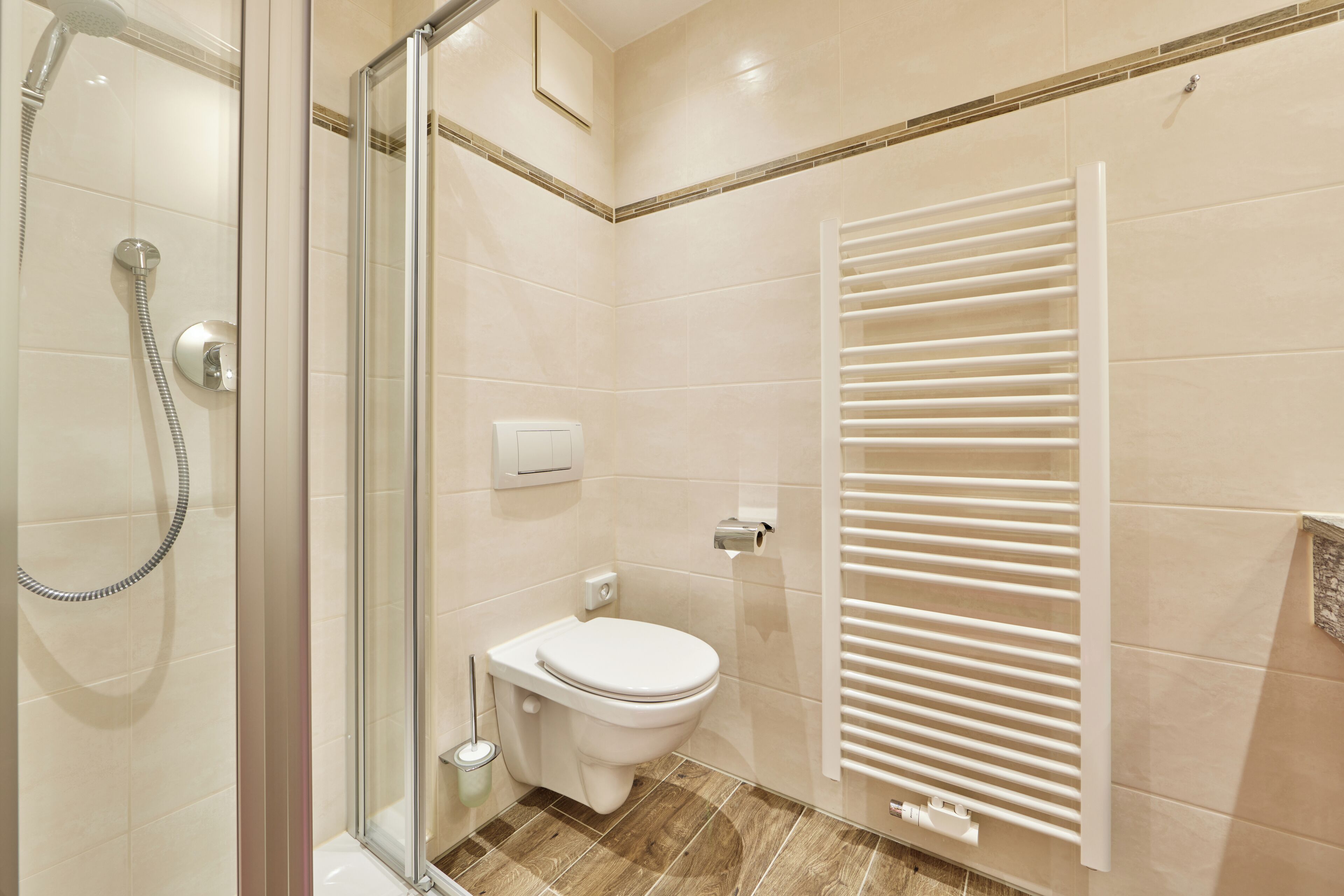 Een moderne badkamer met een glazen douchecabine, toilet en een ingebouwde handdoekhouder.