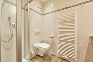 A modern bathroom with a glass shower enclosure, a toilet, and a built-in towel rack.