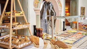 A buffet with various food items and bread baskets. - Alpenhotel Rieger (Mittenwald)
