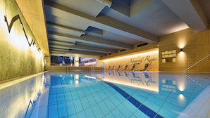 A swimming pool with tiled flooring and a wooden wall with a sign. - Alpenhotel Rieger (Mittenwald)