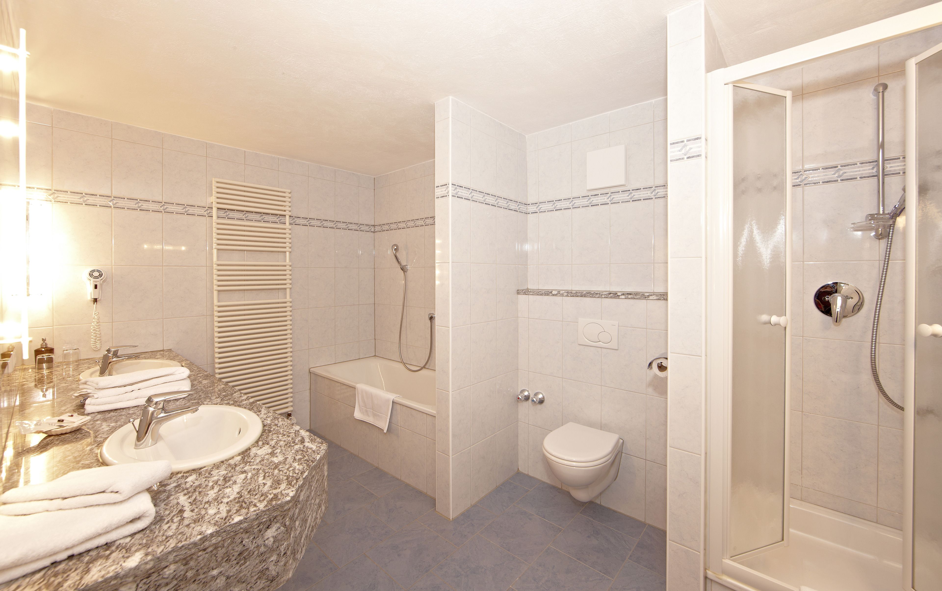 Une salle de bain équipée d’un lavabo, d’un miroir, d’un porte-serviettes, de toilettes et d’une douche.